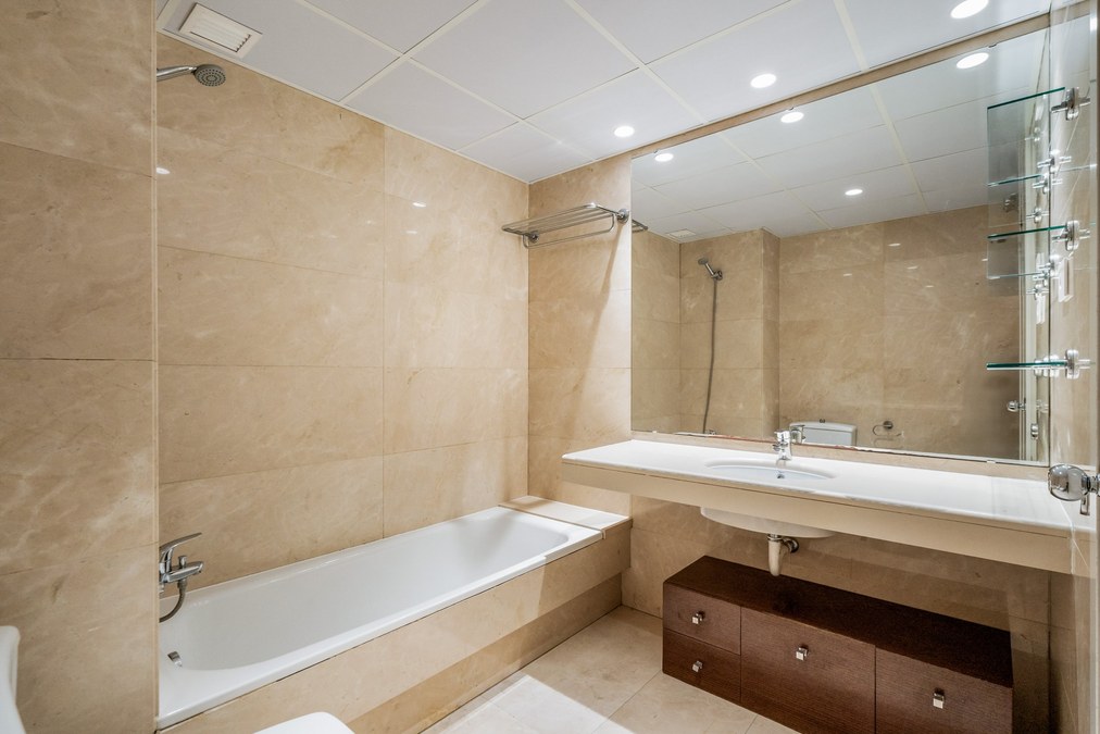 Baño en tonos beige con bañera, lavabo y espejo grande