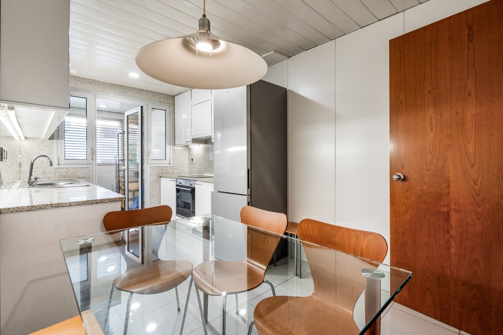 Zona office de la cocina con mesa de cristal y sillas de madera